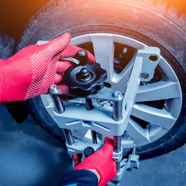 Monteur prüft Radaufhängung und Bremse am angehobenen Fahrzeug